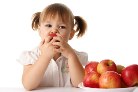 Cute child eats red apple, isolated over white