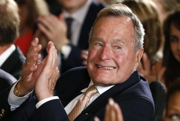 Former President George H. W. Bush applauds during an event to honor the winner of the 5,000th Daily Point of Light Award at the White House in Washington