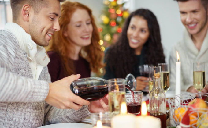 man pouring wine to his friendÂ´s glas while having christmas dinner