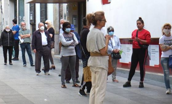 Personas esperan en la cola de un banco.