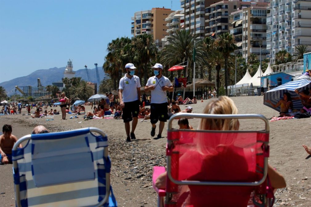 Una pareja de Vigilantes de la playa de Andalucía asesoran a bañistas sobre las medidas preventivas