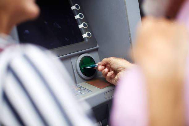 Senior couple somewhere in the city using ATM cash machine.