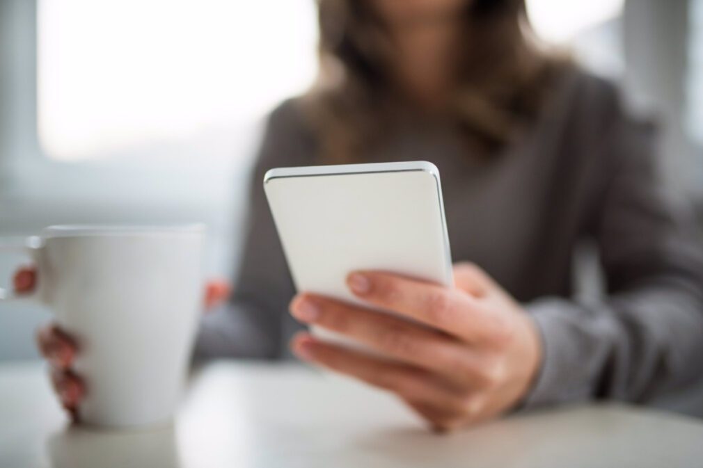 mujer sujetando taza y movil telefono