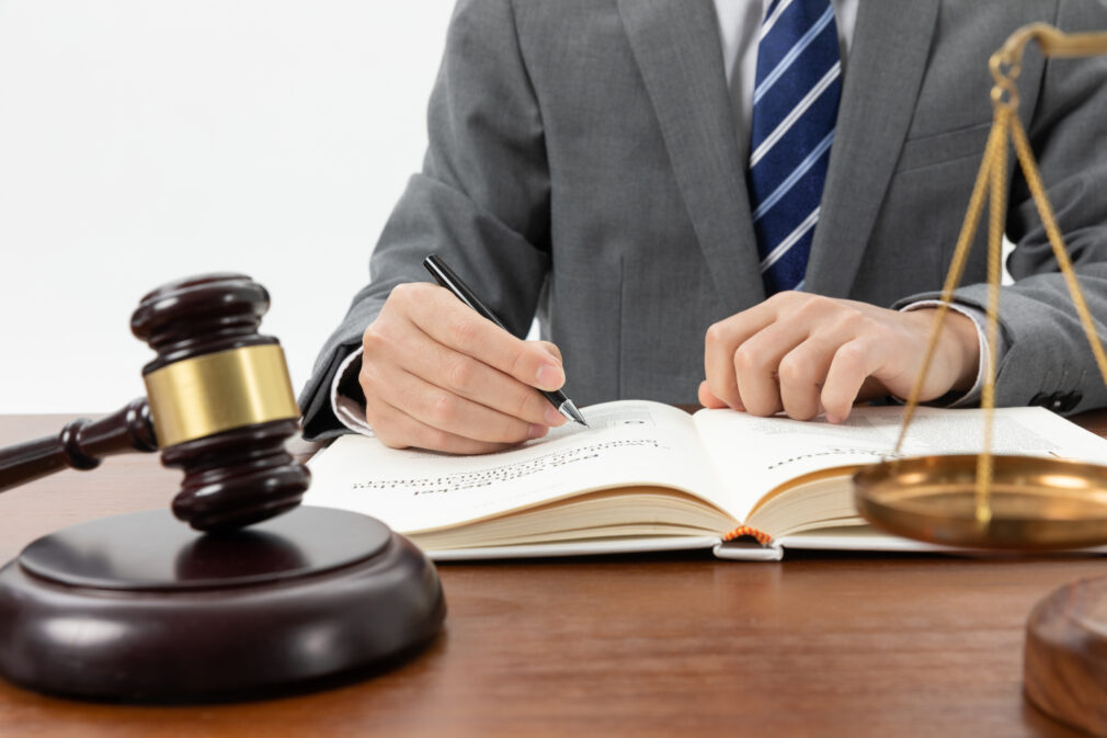 closeup-shot-of-person-writing-in-book-with-gavel-on-the-table