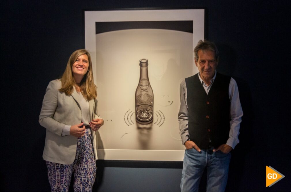 Chema Madoz y la responsable de Cervezas Alhambra posan junto a una de las muestras de la exposición